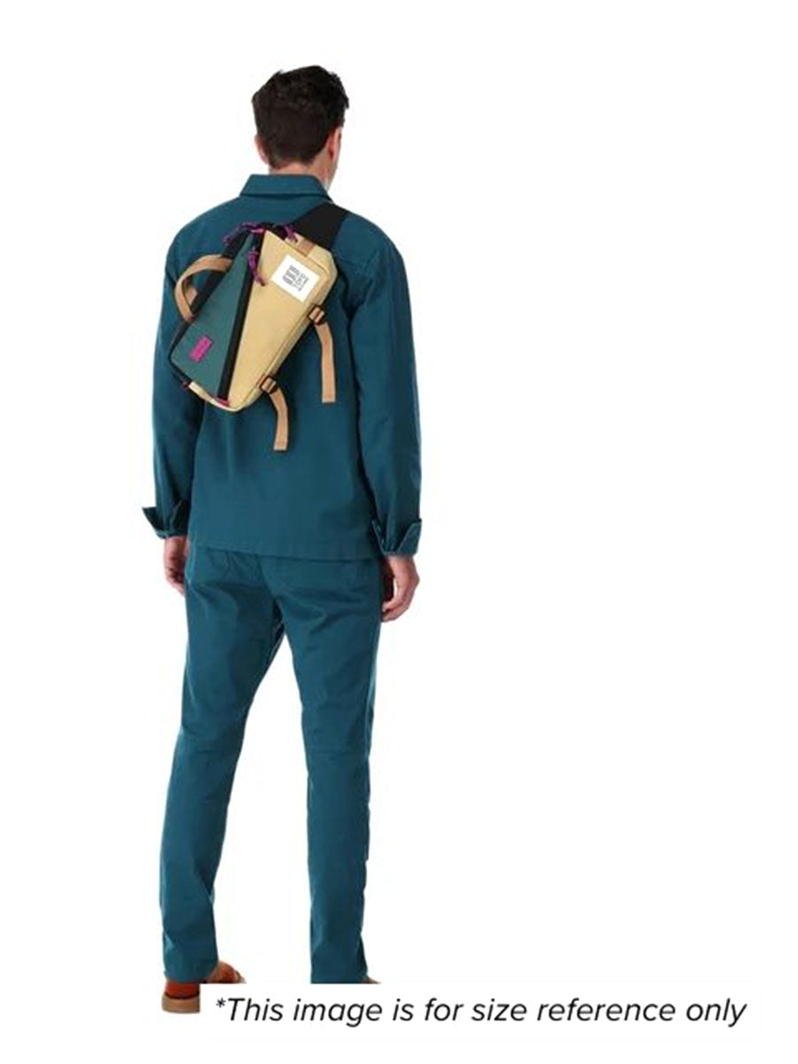 A man showcasing a beige and blue quick pack wearing it over his shoulder for size reference.