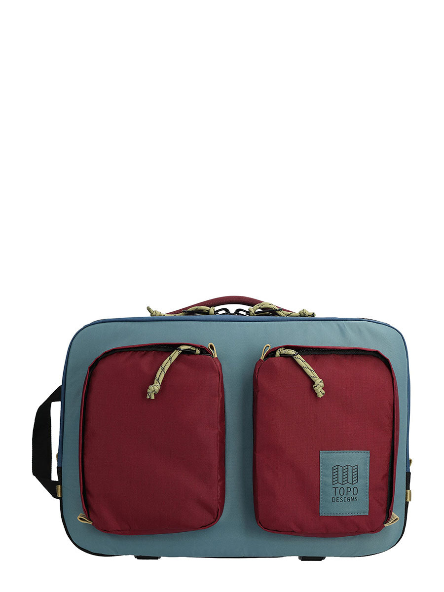 A gray and red briefcase backpack with an external laptop compartment and mesh pockets, with the TOPO Designs logo visible.
