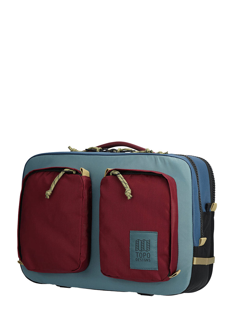 A gray and red briefcase backpack with an external laptop compartment and mesh pockets, with the TOPO Designs logo visible.