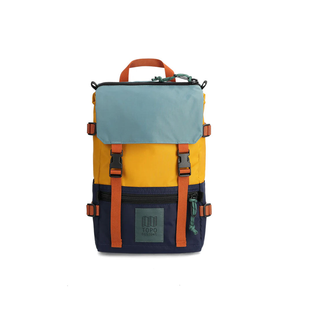 A Rover Pack Mini Backpack with top handle, featuring a combination of blue, yellow, and navy colors with orange straps and buckles.