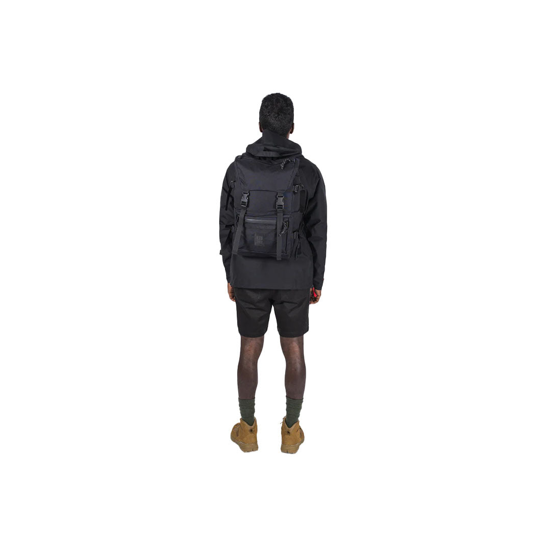 A man showcasing black Rover Pack Tech backpack wearing it on his back for size reference.