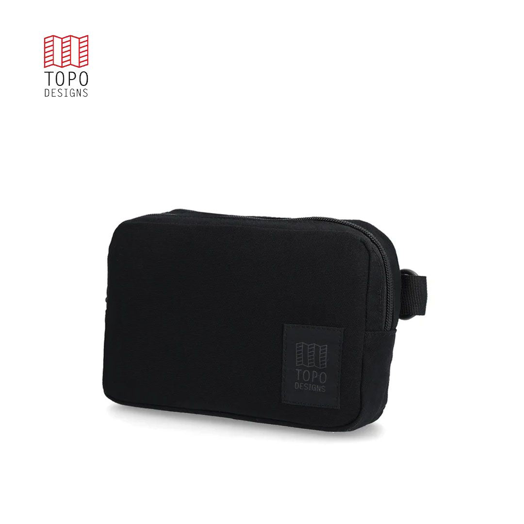 A black dirt belt bag with zippered compartments and an adjustable web belt, featuring the TOPO brand logo.