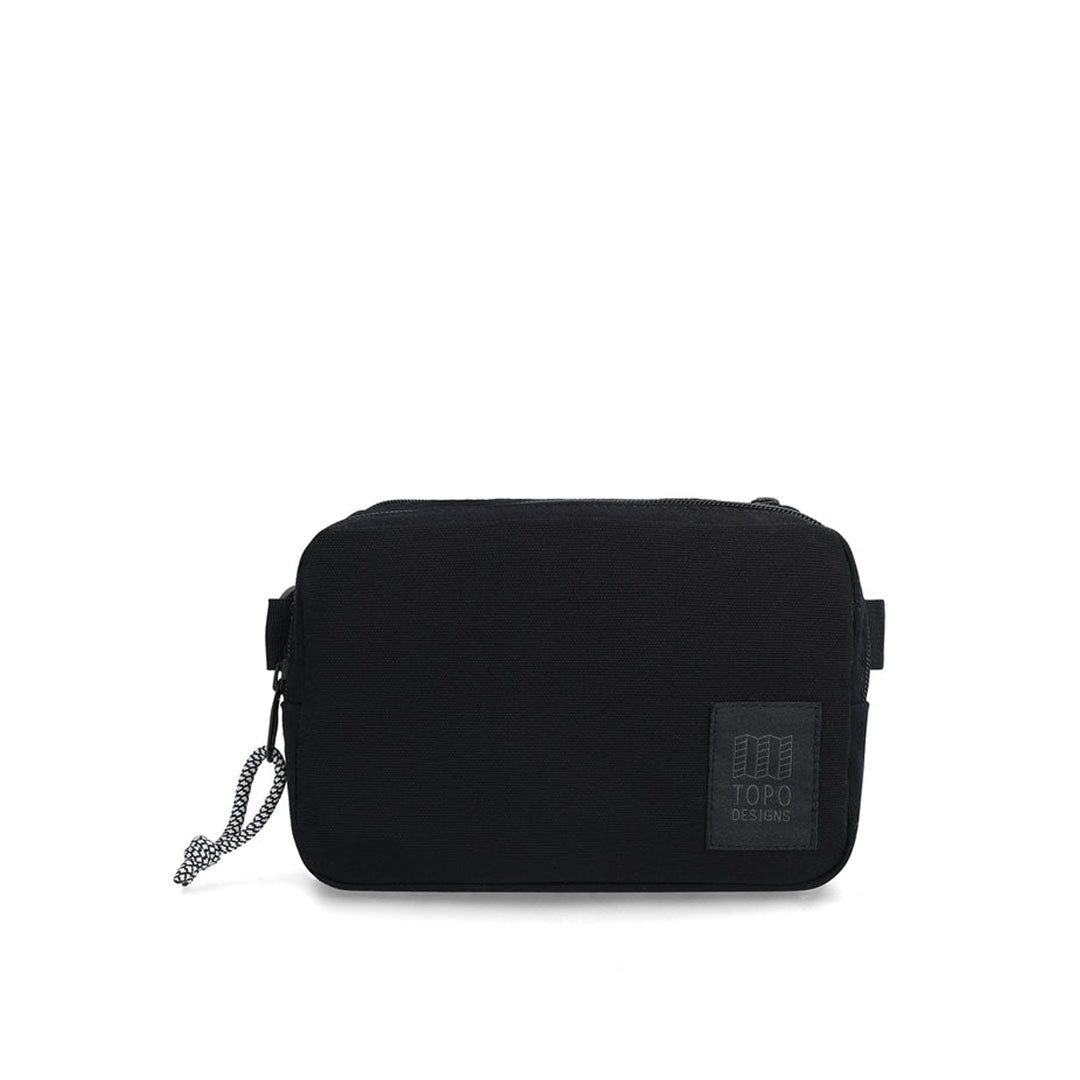 A black dirt belt bag with zippered compartments and an adjustable web belt, featuring the TOPO brand logo.
