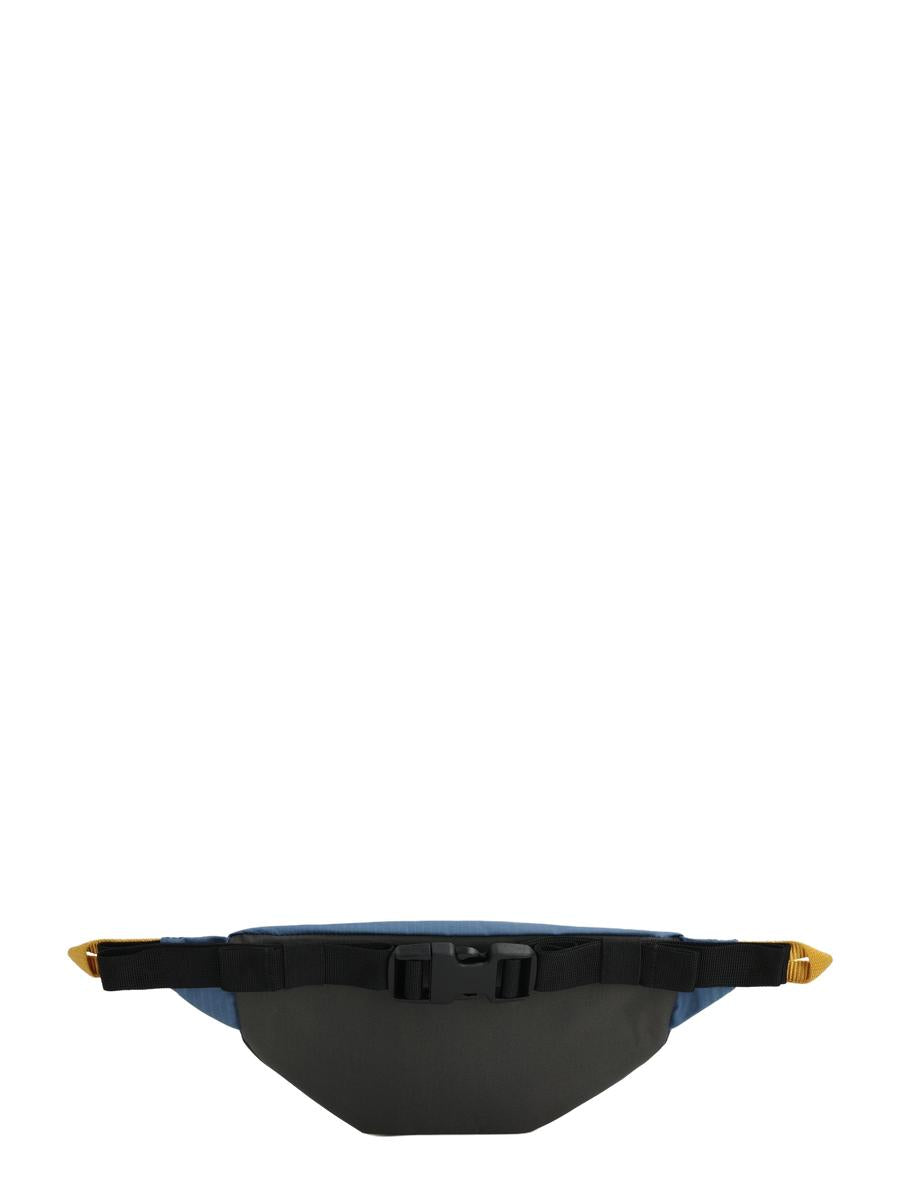 A backside view of a black and beige waist pack with heavy duty zippers and a seatbelt webbing strap, featuring two pockets.